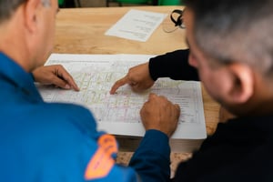 two people reviewing a blueprint and discussing details on construction